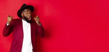 Noel ve insanlar kavramı. Mutlu siyah adam yeni yılı kutluyor ve dans ediyor, parti kıyafeti giyiyor, kırmızı arka plan.