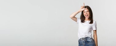 Şımarık, güzel bir kız gülümseyen ve alay eden biri, alnında ezik bir jest yapıyor..