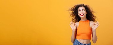 Kaygısız ve mutlu şehir kadını. Burun halkası ve kıvırcık saç stili. Pervasız ve umursamaz bir şekilde avuçlarını kaldırıyor.