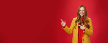 Yaşam tarzı. Neşeli, arkadaş canlısı ve enerjik, sarı montlu yardımsever kızıl saçlı kız sol üst köşeyi işaret ediyor ve tatmin olmuş bir şekilde gülümsüyor.