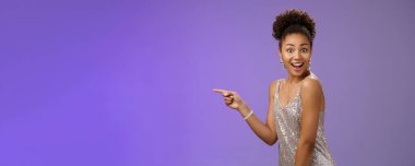 Etkileyici, zarif, afrikalı bir kız. Parlak, gece elbisesi parıldıyor. İşaret parmağı sola dönüyor..