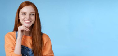 Şık, kendine güvenen, zeki, yaratıcı kızıl saçlı kız neşeli, düşünceli, düşünceli, düşünceli, önerili, dokunaklı, gülümseyen, onaylı, dostça konuşan, mavi önlüklü kız..