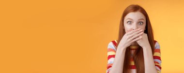 Özür dilerim. Kendini garip hisseden bir kız uygunsuz sözler sarf ediyor. Kendine güvensiz, ağzı açık, gözleri açık kameraya bakıyor. Şaşırmış bir şekilde turuncu arka planda duruyor..