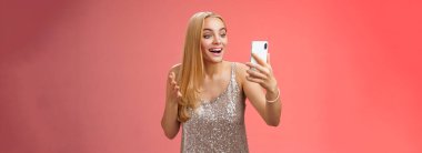 Yakışıklı, güzel, güzel, sarı elbiseli, video konuşması yapan akıllı telefon görüntüsü sunan, neşeli, neşeli, neşeli, hoş, sarışın bir kız. Balo kıyafetini gösteren kardeşinle sohbet ederken mutlu ol..