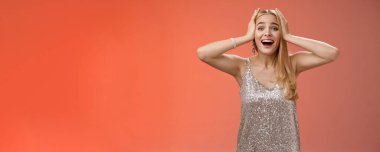 Şaşırmış, heyecanlı, gümüş renkli şık elbiseli sarışın kadın kendi şansına inanamıyor. Mutluluk el ele tutuşuyor. Gülümsüyor, haykırıyor, hayrete düşürüyor..