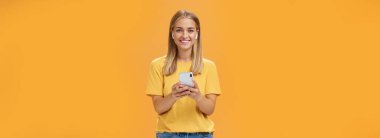 Dost canlısı karizmatik ve yakışıklı genç bir kadının portresi sarı tişörtlü, akıllı telefon takan, kablosuz kulaklık takan spor salonuna giderken müzik dinlemenin keyfini çıkaran. Teknoloji ve