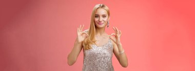 Kaygısız, iyimser, genç, sarışın kadın her şeyin mükemmel yapıldığına emin ol. Harika bir sonuç göster. Tamam, gülümseyen, kendine güvenen, güler yüzlü, güler yüzlü, lüks elbise, kırmızı arka plan..