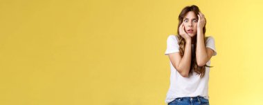 Aman Tanrım, biri beni kurtarsın. Korkmuş, sersemlemiş, paniğe kapılmış genç bir kadın, kamerayı kapıyor, korkmuş, ağzı açık, soluk soluğa kalmış, sersemlemiş, sarı arka planda ürkek, güvensiz..