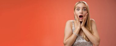 Şok olmuş nutku tutulmuş endişeli genç kadın nefes nefese kalmış endişeli çene dokunuşları geniş gözler şaşkınlık içinde kameraya bakıyor korkmuş, kırmızı arka plan.