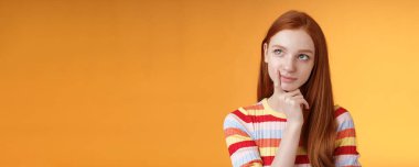 Yaratıcı, düşünceli, genç, zeki, kızıl saçlı, fikir üreten kız öğrenci projesine bak sol üst köşede rüya gibi dokunaklı dudak okuma seçimi, önemli bir karar alma sırası, turuncu arka plan..