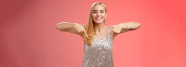 Yaşam tarzı. Çekici, alımlı, sarışın, gümüş parıltılı elbisesi olan, gülümseyen, heyecanlı, harika bir parti mekanında takılmayı deneyen, mutlu, kırmızı arka planda dikilmeyi seven, neşeli, çekici bir kadın.