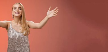 Cana yakın, sevimli, çekici, çekici, gümüş elbiseli, misafirleri karşılayan, hoş geldin partisi veren, kucaklayan, kucaklayan, gülümseyen, kırmızı arka planlı, sevimli, çekici bir doğum günü kızı..