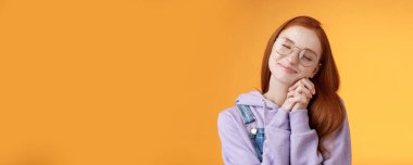 Tatlı, mutlu, romantik, kızıl saçlı kız arkadaş. Gözlerini kapat. Hayal kuran, hayal kuran, tatlı, güzel anıları hatırlatan, turuncu arka planda duran, hayal kuran, güzel manzaralar..