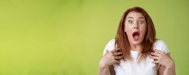 Paniğe kapılmış orta yaşlı, soluk soluğa kalmış, ağzı açık, kameradan korkan, sinirli sinirli, sinirli, sinirli, yeşil arka planı olan bir kadın..