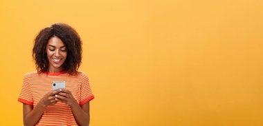 Alet ekranına sevinçle gülümseyen akıllı telefon uygulaması üzerinden parti davetiyesine cevap yazmak, komik oyun oynamak, turuncu duvarın üzerinden metroda zaman harcamak