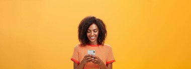 Alet ekranına sevinçle gülümseyen akıllı telefon uygulaması üzerinden parti davetiyesine cevap yazmak, komik oyun oynamak, turuncu duvarın üzerinden metroda zaman harcamak