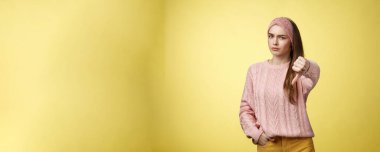 Hiç hoş değil. Hüsrana uğramış ve hoş olmayan, örgü örülmüş süveter giyen hoş bir kadın. Kaşları çatık, ters sırıtan, yargılayıcı bir tavır sergiliyor. Sarı duvardaki kötü durumu onaylamadığını belirtiyor..