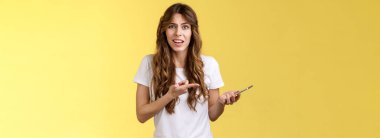 You kidding me. Pissed displeased unsatisfied curly-haired girl frowning grimace bothered look camera complaining bad service finish intense disappointing phone call hold smartphone pointing mobile.