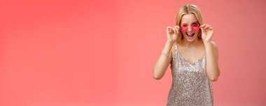 Yaşam tarzı. Şımarık, kaygısız, genç, sarışın, küstah, küstah, kendine güvenen, yakışıklı erkek gece kulübüne ilk adımı atan, kırmızı arka planda dans eden, güneş gözlüklü, gözlüklü bir kız.