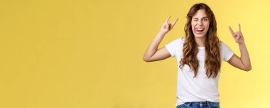 Harika parti eğleniyor. Cesur, çekici, kaygısız bir kız eğleniyor. Rock-n-roll şovu, heavy metal jestleri, komik ifadeler, göz kırpan dil, eğlenceli sarı arka plan..