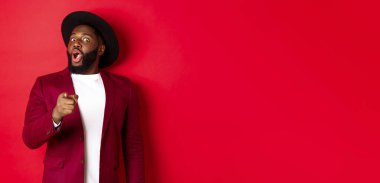 Şok olmuş siyahi adam hayret içinde kamerayı işaret ederek kırmızı ceketli ve şapkalı birini tanıdı..