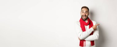 Noel tatili ve kutlama konsepti. Heyecanlı sakallı erkek alıcı logonuzu gösteriyor, reklam teklifini işaret ediyor, beyaz arka planda duruyor..