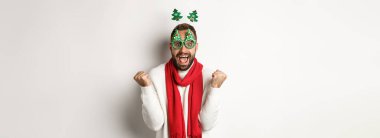 Noel, yeni yıl ve kutlama konsepti. Heyecanlı adam ödülü, kış terfisi, yumruk tokuşturma ve kutlama, parti gözlüğü, beyaz arka plan.