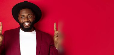 Yakışıklı, sakallı, barış işaretleri gösteren, mutlu gülümseyen, kırmızı arka planda duran siyah adamın yakın çekimi..