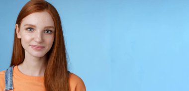 Çekici kızıl saçlı mavi gözlü kız turuncu tişörtler giyiyor. Keyifli bir şekilde gülümsüyor. Keyifli bir şekilde konuşuyor..