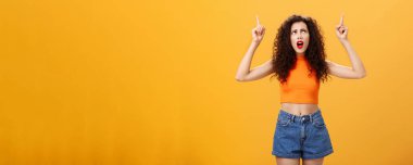 Kıvırcık saçlı, aptal ve dengesiz Avrupalı parti kızı. Kırmızı rujlu ve şık portakallı üst taraf kötü havadan şikayet ediyor, elleri kaldırıyor ve mutsuz bir yüzle yukarı bakıyor..