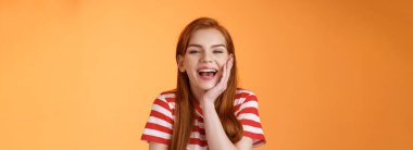 Sevimli, güler yüzlü, kızıl saçlı bir kadın arkadaşlarıyla konuşuyor. Mutlu bir şekilde gülüyor. Sağlıklı, dişlek, beyaz bir gülümseme sergiliyor..