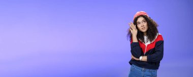 Sıkılmış, kendine güveni yüksek, sokak tarzı giyinmiş, kibirli, havalı bir kızın belden aşağı vuruşu. Gözleri yuvarlanarak facepalm yapıyor ve asabiyet ve hayal kırıklığından asılıyor. Mavi arka planda poz veriyor..