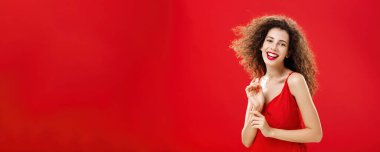 İnce, zarif, kaygısız, kırmızı şık gece elbisesi içinde kıvırcık saçlı, tatlı tatlı gülümseyen ve saçı havada uçuşan ürkek ve nazik bir kadının belden yumağı. Reklam.