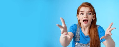 Kapalı kapılar ardında hayal kırıklığına uğramış tatlı, kasvetli, kızıl saçlı kız, ellerini kaldır tam bir inançsızlık, somurtkan, sinirli, rekabeti kaybeden, kötü sonuçlar alan, mavi arka planda mutsuz dur.