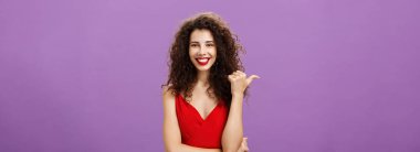 Çıkış yapmanızı öneriyor. Çekici, neşeli ve arkadaş canlısı, kıvırcık saçlı, akşam kırmızı elbiseli, başparmağını gösteren, kendinden emin ve kendinden emin, kopya alan gösteren Avrupalı kadın..