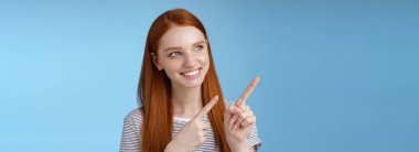 Çekici kızıl saçlı, saf, temiz, kızıl, uzun saçlı, sola bakan, ilgi çekici bir gülümseme. Yeni ürün, mavi arka plan, ilgi çekici bir reklam..