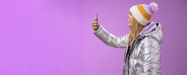 Yaşam tarzı. Kaygısız, çekici, beyaz, beyaz, ceketli bir kız. Kolunu uzat, akıllı telefon kaydı yap, bağır, ağzını aç, gözlerini kapa, komik suratları taklit et.