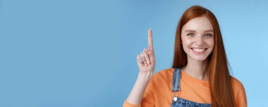 Kendinden emin, mutlu, karizmatik, mavi gözlü kız çilleri ürünü kaldırmaya yardımcı oluyor. İşaret parmağı kaldırıyor, fotokopi alanını işaret ediyor. Gülümsüyor..