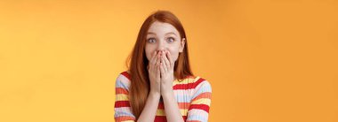 Şaşırmış, çekici, güzel, kızıl saçlı kız inanılmaz bir şans elde etti. Şaşırmış bir gülümseme, nefes nefese kalmış, ağzı açık avuçlar açık, mutlu bir şekilde tepki veriyor. Harika bir haber, turuncu arka plan..