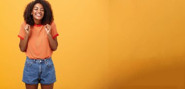 Geziden dönen aşığı görmek için hevesli kız heyecanlı ve heyecanlı mutlu gülüşle gülümseyen yumrukları kapalı gözlerle sırıtan neşeli ve turuncu arka planda eğlenen. Yaşam biçimi.