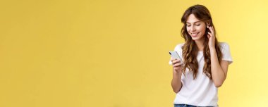 Yumuşak, kıvırcık saçlı kadın tişörtü, kablosuz kulaklık, kulaklık, gülümseme, akıllı telefon ekran müziği, müzik dinlemek istiyorum.