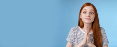 Yapışkan, sevimli, kızıl saçlı Avrupalı kız ellerinizi bir araya getirerek lütfen kabul edin ya da mavi arka planda durmak için yalvarın deyin. Boşluğu kopyala