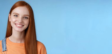 Neşeli, kızıl saçlı, mutlu gülümseyen beyaz kız kameraya mutlu bak samimi dostça konuş yaz tatillerinde arkadaşlarınla sohbet et mavi arka planda neşeli dur. Boşluğu kopyala