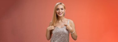 Kendini beğenmiş, yakışıklı, kendine güvenen, gümüş renkli, lüks elbiseli, kendine güvenen, kendini beğenmiş, gururla övünen, kendi başarılarından bahseden, kırmızı arka planda duran, kendine güvenen, kendine güvenen sarışın kadın..