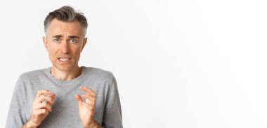 Endişeli orta yaşlı bir adama yakın plan, korkmuş ve gergin görünüyor, suçlu hissediyor, beyaz arka planda duruyor..