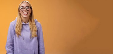 Eğlenceli kadın programcı, öğle arasında iş arkadaşlarının etrafında dolanıyor. Kocaman gülümsüyor, sevimli gözlüklerle gülüyor, mor kapüşonlu, mor arka planda duruyor..