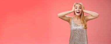 Şaşırmış, heyecanlı, gümüş renkli şık elbiseli sarışın kadın kendi şansına inanamıyor. Mutluluk el ele tutuşuyor. Gülümsüyor, haykırıyor, hayrete düşürüyor..