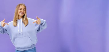 Kendinden emin, bronz tenli, açık renk saçlı, kendine özgü yetenekleri ve başarılarıyla övünen yeni kapüşonlu kapüşonlu içinde harika hisseden neşeli genç kız. Vücut