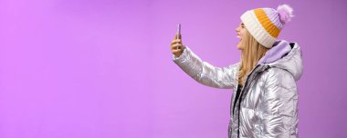 Yaşam tarzı. Kaygısız, çekici, beyaz, beyaz, ceketli bir kız. Kolunu uzat, akıllı telefon kaydı yap, bağır, ağzını aç, gözlerini kapa, komik suratları taklit et.