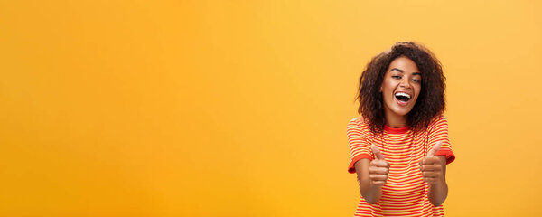 Woman surely knows how boost mood. Portrait of friendly-looking stylish and outgoing african american girlfriend with curly hairstyle showing thumbs up in like and approval agreeing to friend idea.